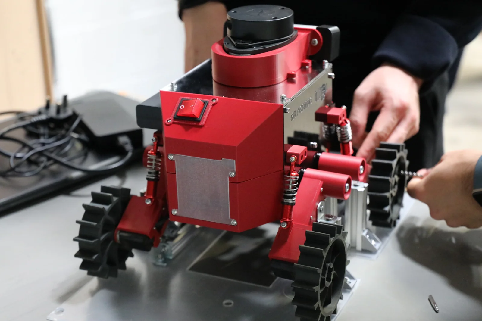 Team members working on a rover wheel while the chassis rests on a stand.