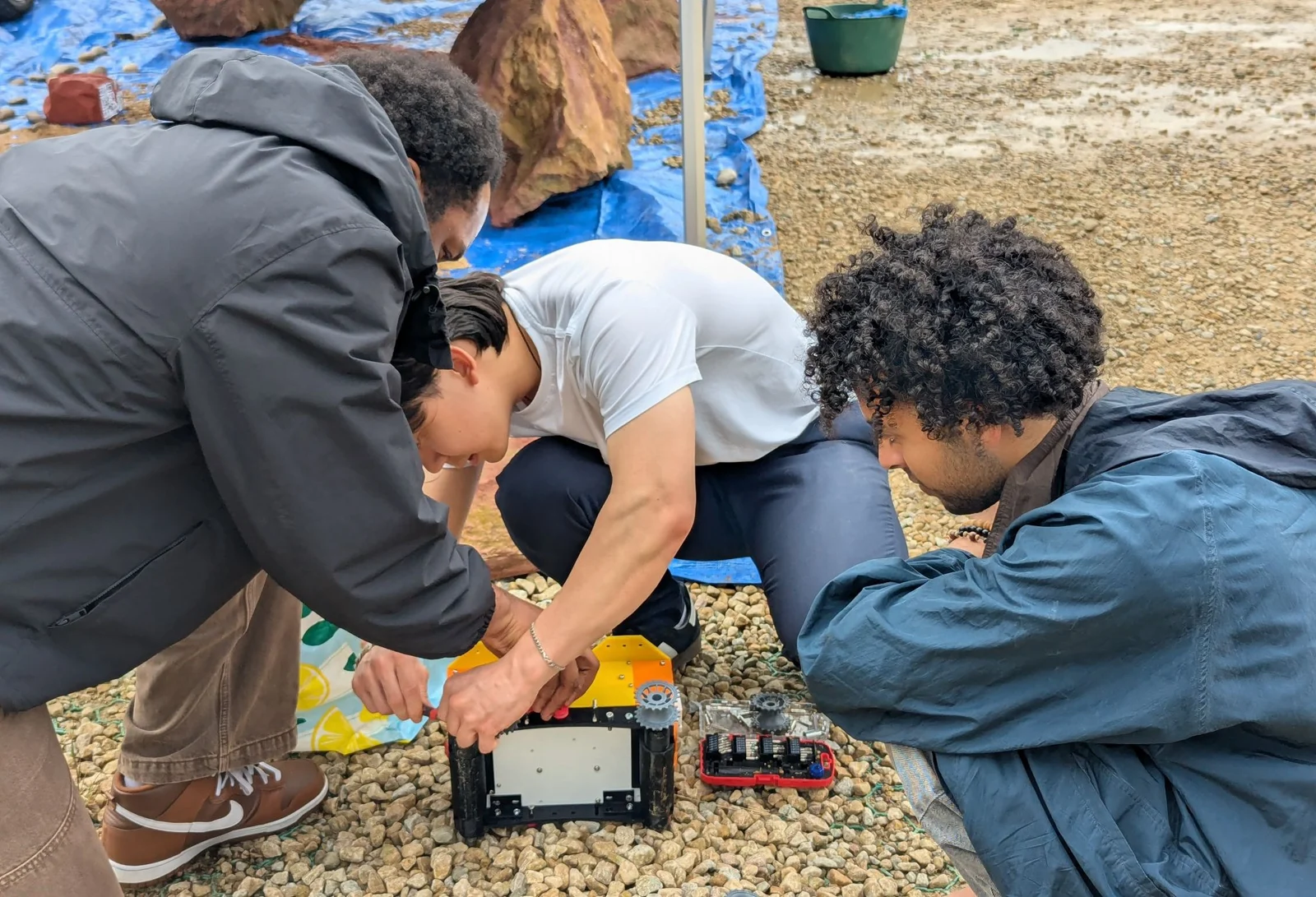 Team members working on the tracked rover outdoors.