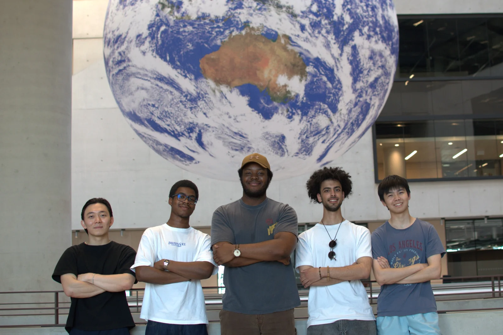 Five MarshGazers team members standing beneath a large globe display.