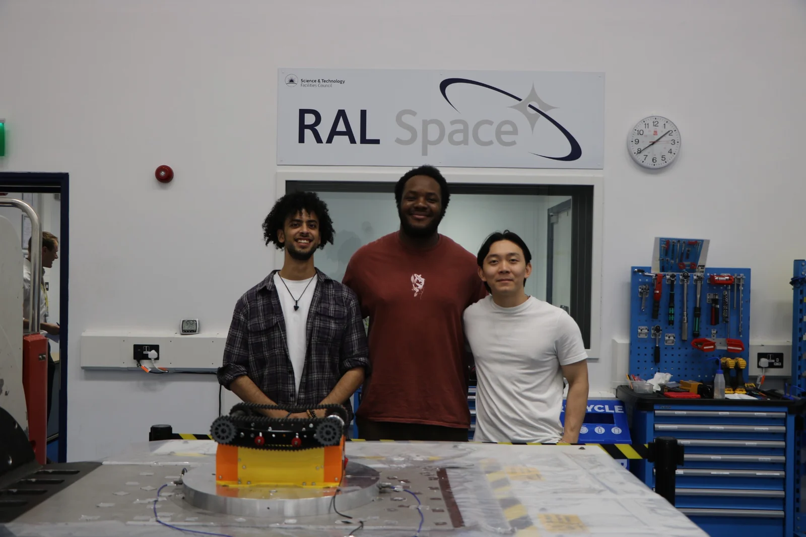 Three MarshGazers team members standing with the rover in a RAL Space laboratory.