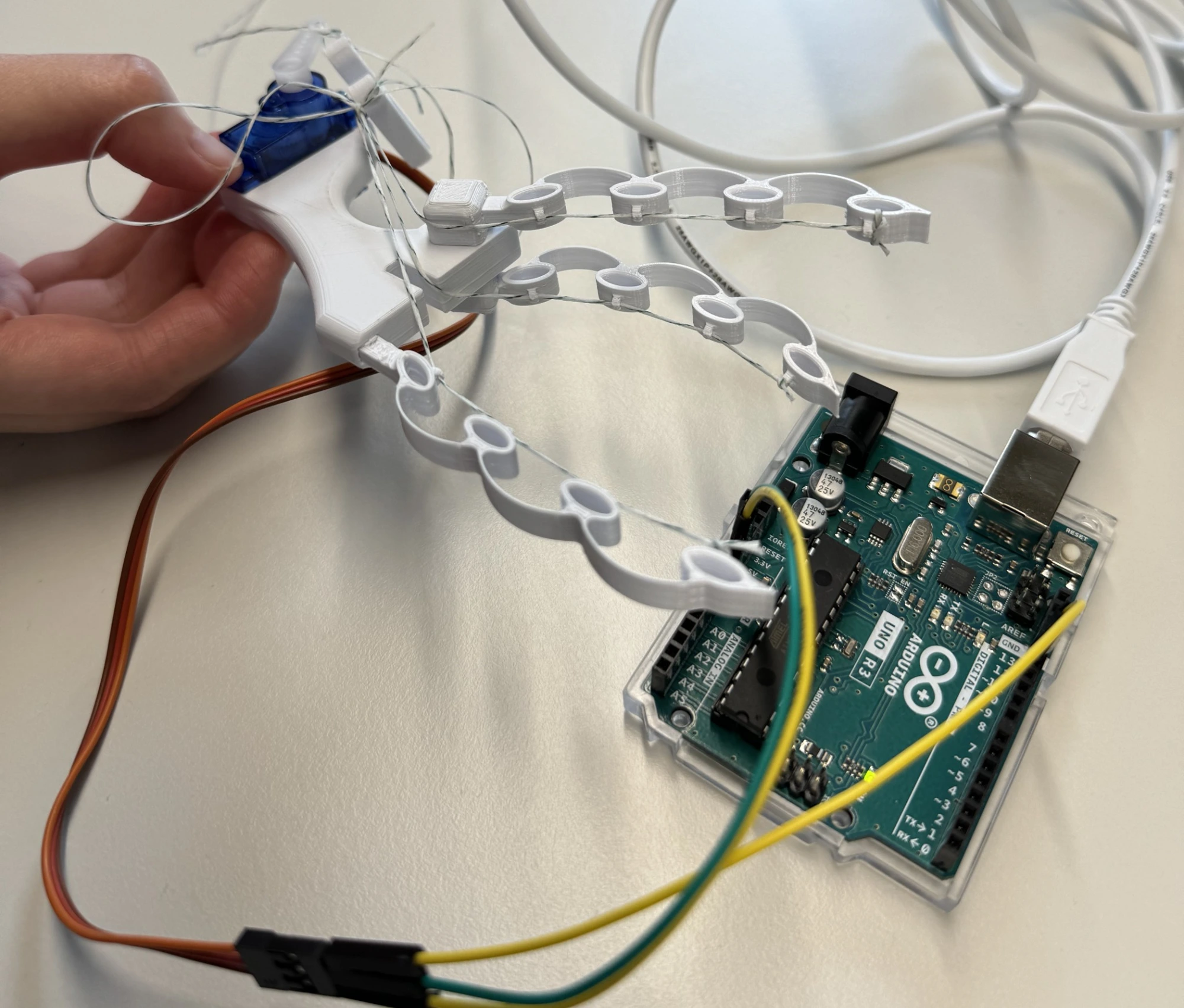 Close-up of the compliant string-actuated gripper prototype and its electronics