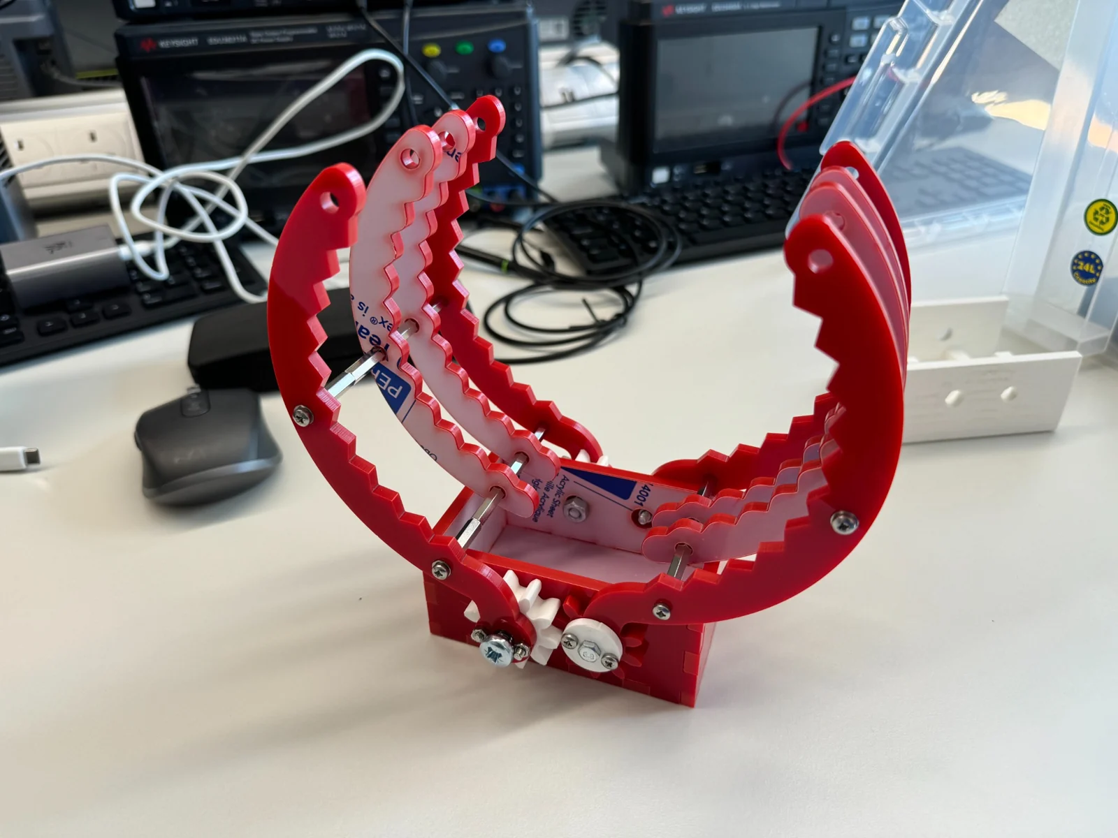 Red acrylic rigid gripper prototype with geared actuation.